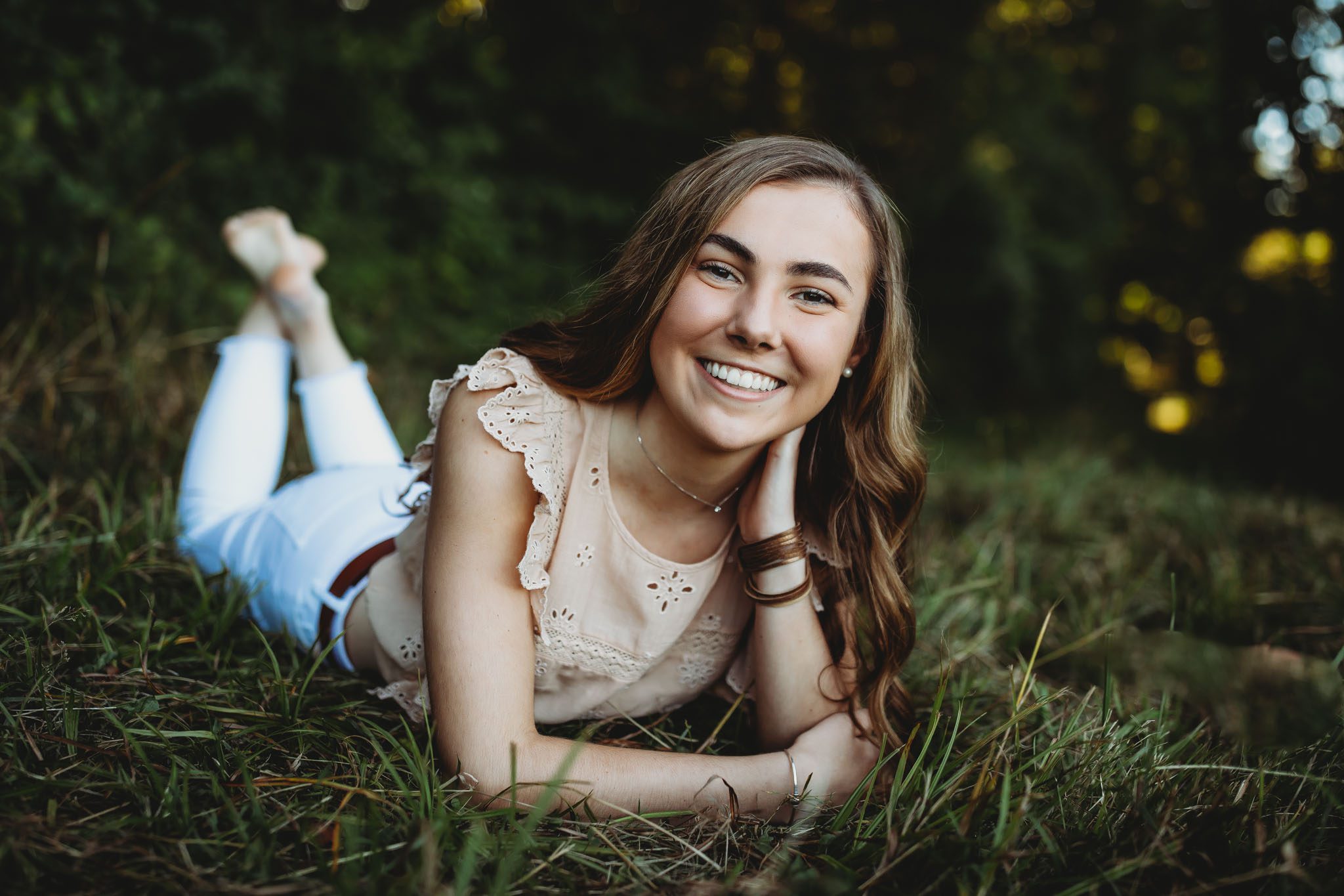 Senior portrait of a young woman laying in a field of grass at sunset in Massachusetts photographed by Sean Wytrwal of J&S Photography