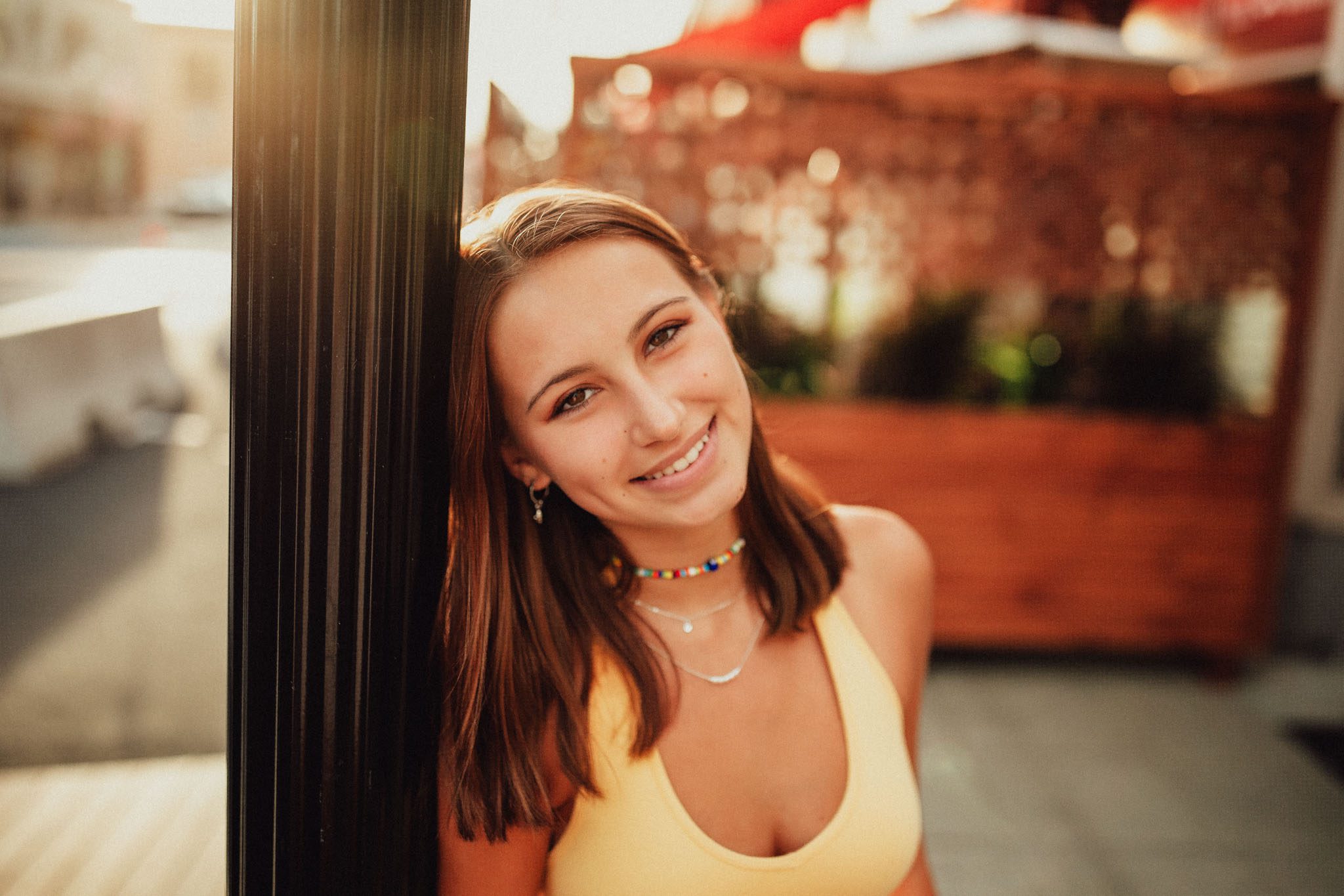 Summer senior portrait of a young woman leaning against a lamp post in a city in Massachusetts photographed by Sean Wytrwal of J&S Photography