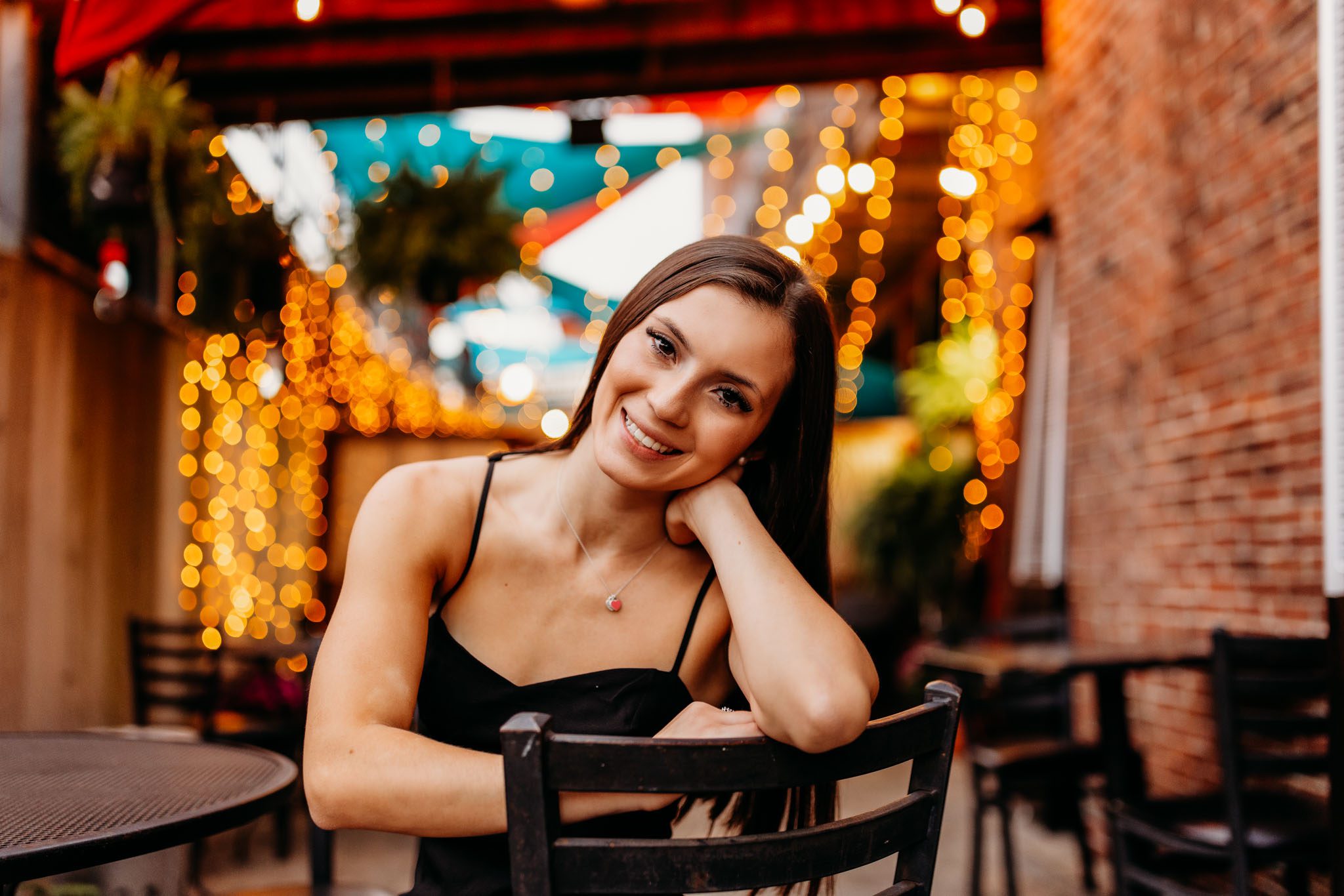 Summer senior portrait of a young woman in a black dress at a restaurant patio in Massachusetts photographed by Sean Wytrwal of J&S Photography