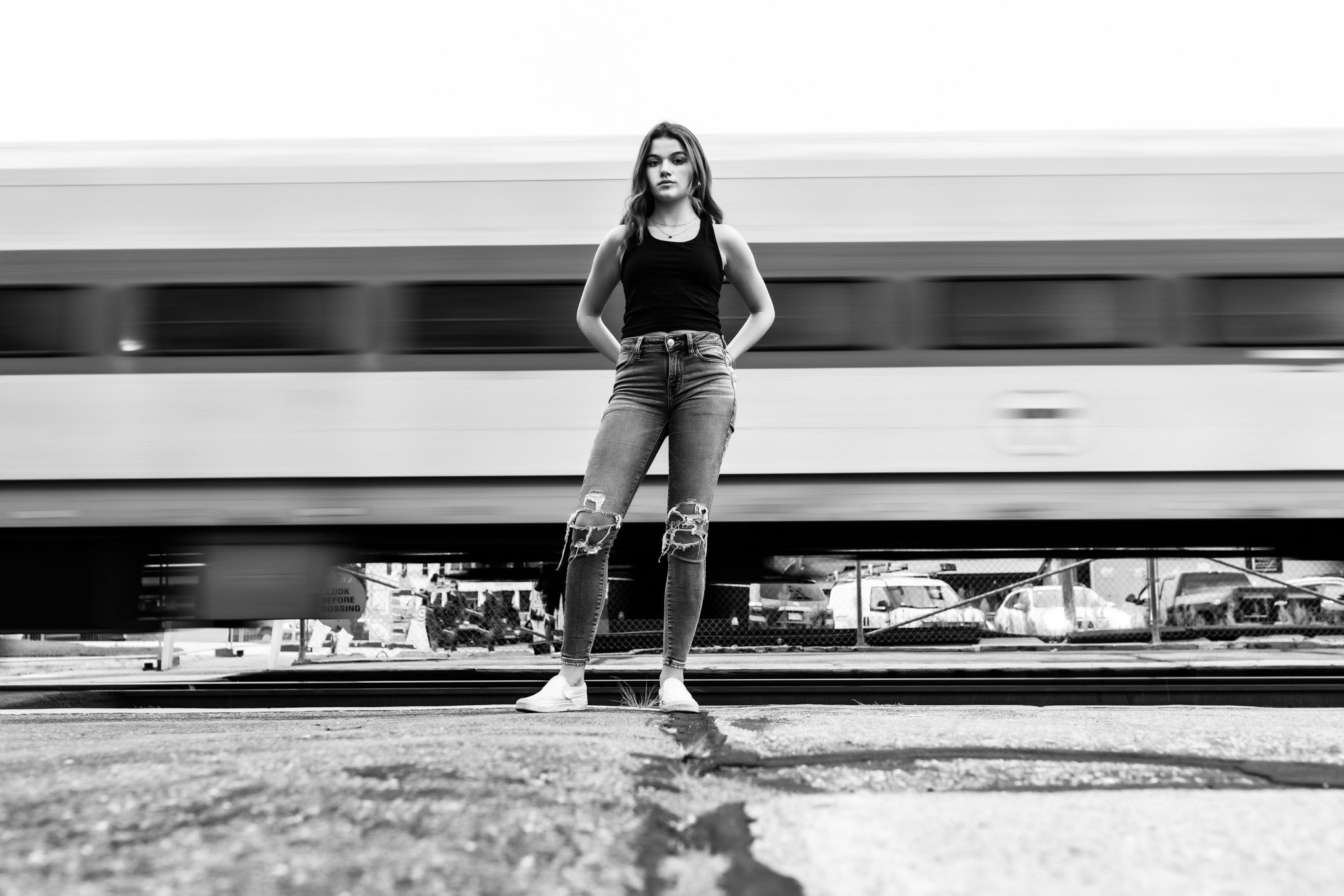 Urban Black and white senior portrait of a young woman standing in front of a moving commuter rail train and train track in Massachusetts