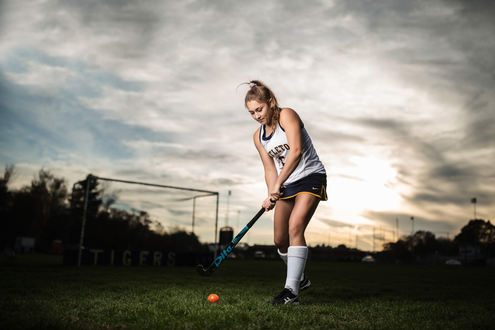 Senior portrait of a young woman playing field hockey at her high school at dusk in Massachusetts photographed by Sean Wytrwal of J&S Photography
