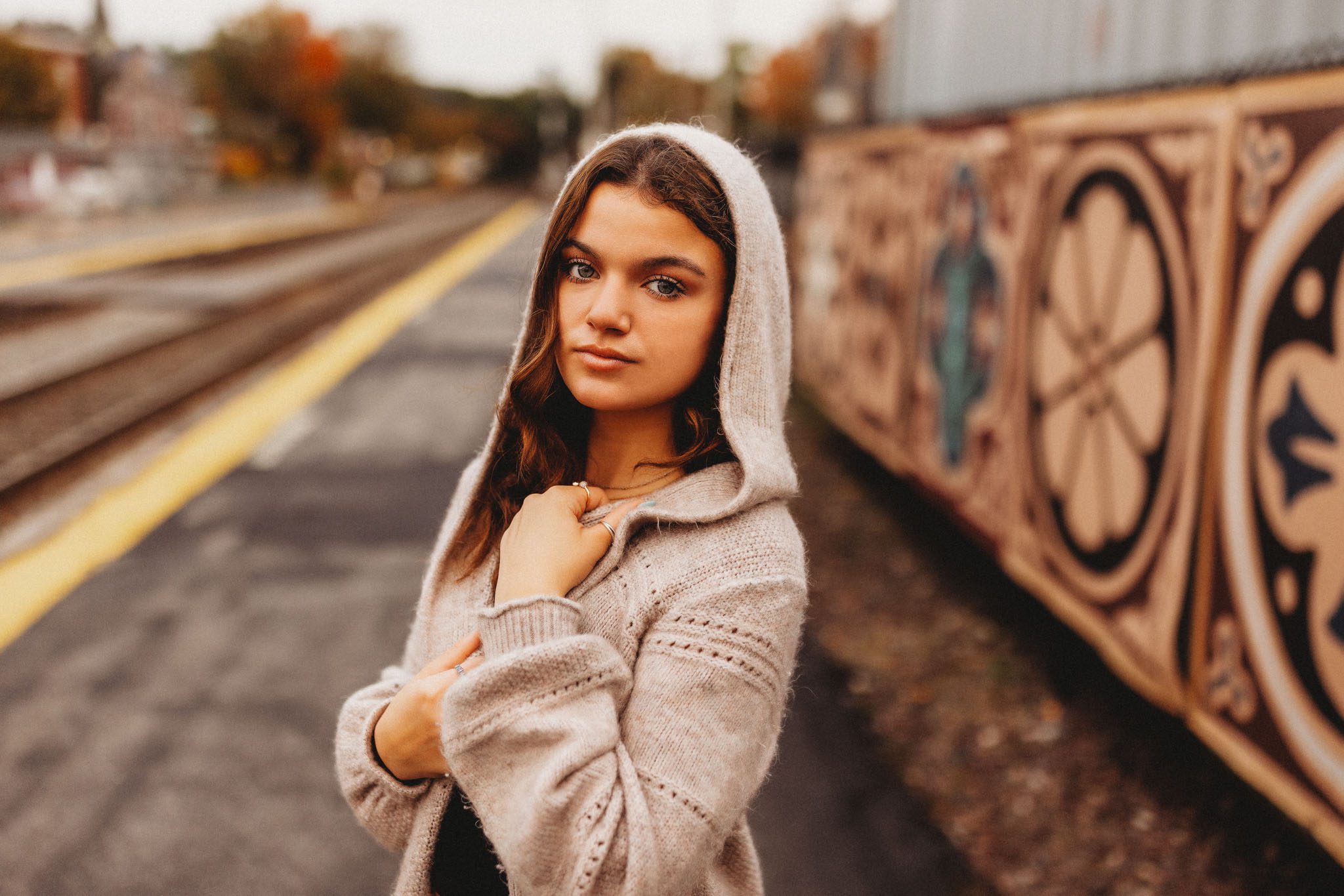 Senior portrait of a young woman wearing a hoodie sweater at a train station in Massachusetts photographed by Sean Wytrwal of J&S Photography